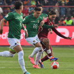 663D5C38 6D5A 430C A39F 4AEFC7805619 En un emocionante encuentro disputado en el Estadio Municipal de El Alto, Bolivia sorprendió a todos al vencer a Venezuela con un contundente 4-0. Este partido, correspondiente a la séptima jornada de las Eliminatorias Sudamericanas para el Mundial de 2026, mostró a una selección boliviana dominante desde el inicio.El primer gol llegó temprano, a los 13 minutos, cuando Ramiro Vaca anotó con un potente disparo desde fuera del área, dejando sin opciones al arquero venezolano Rafael Romo. La presión boliviana continuó y, justo antes del descanso, Carmelo Algarañaz convirtió un penal para poner el 2-0 en el marcador.La segunda mitad comenzó con la misma intensidad. Apenas reiniciado el juego, Miguel Terceros aprovechó un centro raso de Roberto Fernández para marcar el tercer gol de Bolivia. La defensa venezolana no pudo contener los ataques bolivianos, y a los 70 minutos, Marcelo Martins selló la goleada con un cabezazo preciso tras un tiro de esquina.Con esta victoria, Bolivia suma tres puntos cruciales que le permiten salir del fondo de la tabla y soñar con la clasificación. Por su parte, Venezuela deberá replantear su estrategia si quiere mantenerse en la lucha por un cupo al Mundial.